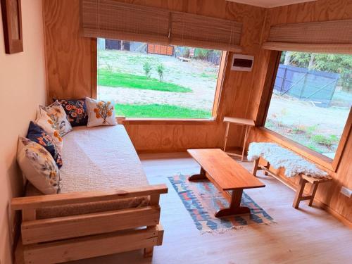 a room with a bed and a table and a window at Cabañas Agua y Campo in Osorno