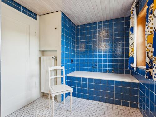a blue tiled bathroom with a chair and a bath tub at Schwermann in Schmallenberg