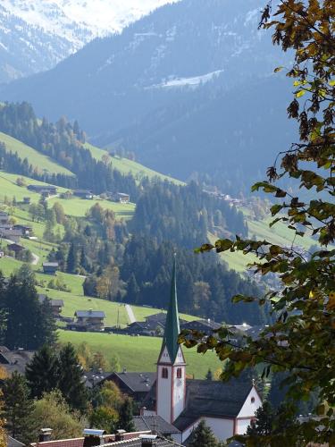 a church with a steeple in a village with a mountain at Anna's Appartement in Alpbach