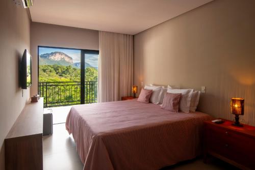 a bedroom with a large bed with a large window at Casa do Valle Hotel Boutique - Vale do Capão in Vale do Capao