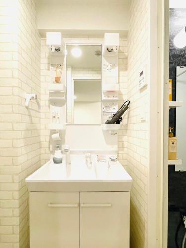 a white bathroom with a sink and a mirror at The Grand Win in Fukuoka