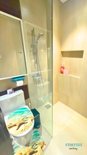 a bathroom with a glass shower and a toilet at Condotel in Tambuli Seaside Studio - F21K in Maribago