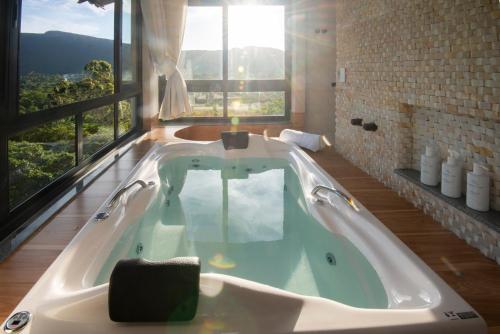 a bath tub in a bathroom with a large window at Casa do Valle Hotel Boutique - Vale do Capão in Vale do Capao