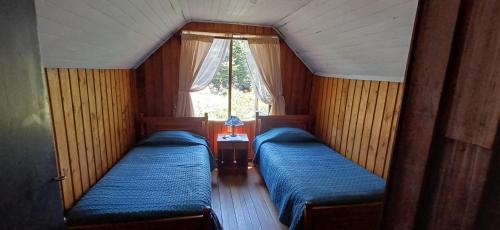 two beds in a small room with a window at Hospedaje Picoyo in Pucón