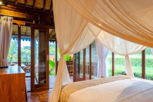 a bedroom with a bed with white drapes at Umah Jati Villa in Gianyar