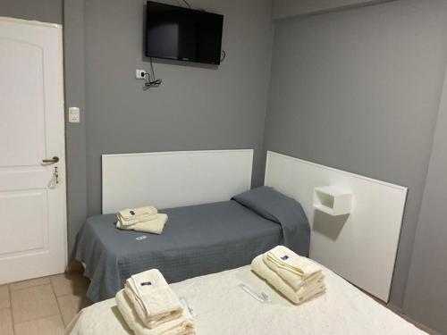 a small room with two beds and a tv at HOTEL EL VIEJO Bar in Perito Moreno