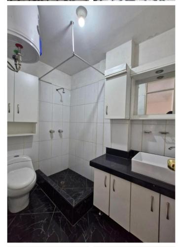 a white bathroom with a toilet and a sink at Modern Apartament Pool & Jacuzzi 2 room in Lima