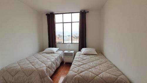 two beds in a room with a window at Modern Apartament Pool & Jacuzzi 2 room in Lima
