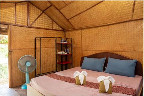 a bedroom with a bed with blue pillows and a fan at Lanta Sunny House in Ko Lanta