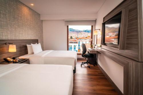 a hotel room with two beds and a window at Hampton By Hilton Cusco in Cusco