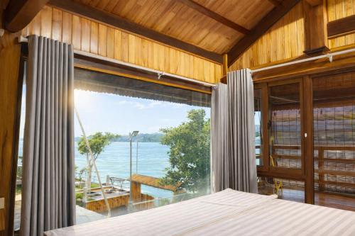 a bedroom with a large window with a view of the ocean at Bon Ben Homestay in Hòa Bình