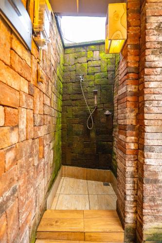 a bathroom with a shower in a brick wall at Sajjana House Bali By Magno in Nusa Dua