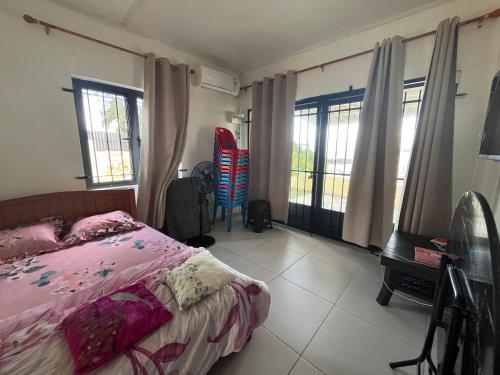 a bedroom with a bed and a desk and windows at Ashan Laksh Bungalow in Grande Rivière Sud Est