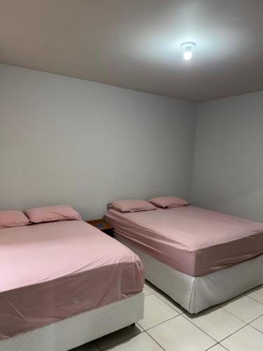 two beds sitting next to each other in a room at Apartamento Sabrina in Curitiba