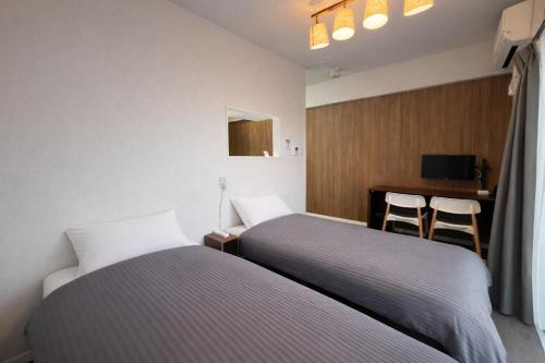 two beds in a room with a desk and a table at Condominium GOLF GOLF Tsuboya in Naha