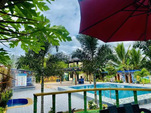 a resort with a swimming pool and a red umbrella at Landayan Traveller Inn in Baco Medio Island