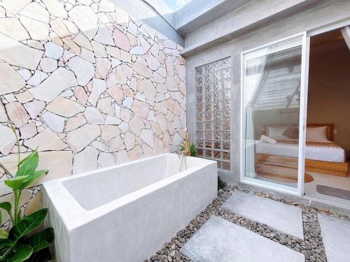 a bath tub in a bathroom with a stone wall at Emerald Beach Homestay in Bình Sum