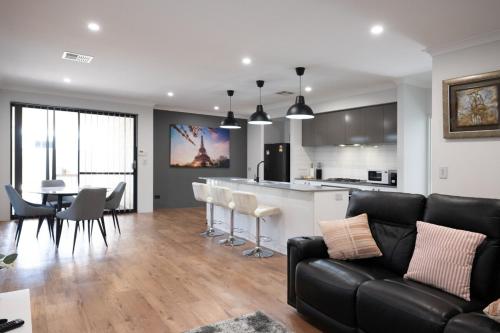a living room with a black couch and a kitchen at Serene Escape Near The Vines & Swan Valley in Upper Swan