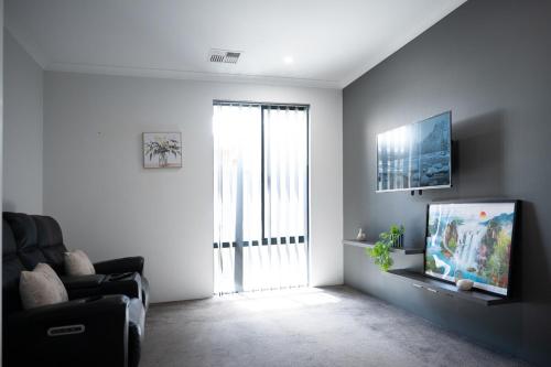 a living room with a couch and a tv and a window at Serene Escape Near The Vines & Swan Valley in Upper Swan