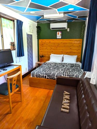 a bedroom with a bed and a desk and a couch at Art Bungalow Amami in Amami