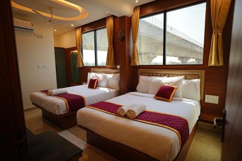 two beds in a hotel room with windows at SN Comforts in Bangalore