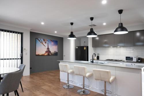 a kitchen with white cabinets and a table and chairs at Serene Escape Near The Vines & Swan Valley in Upper Swan
