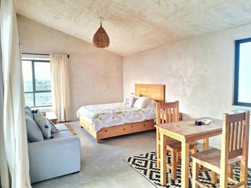 a bedroom with a bed and a table and a couch at Casita Atardecer in Todos Santos