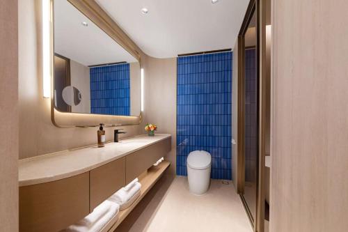 a bathroom with a sink and a toilet and a mirror at Orange Crystal Hotel Wuhan Jinyinhu in Dongxihu