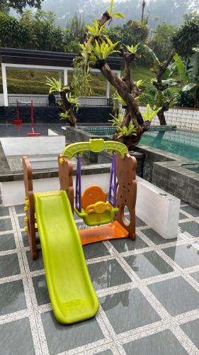 a childs play equipment on a patio next to a pool at Stella Di Mare Puncak with Private Pool 5 Bedrooms in Sampal 2