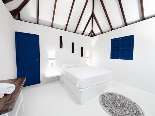 a white room with a blue door and a rug at Hotel Coral Sand Islas Del Rosario in Isla Grande