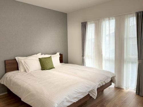 a bedroom with a large white bed with a window at Akikawa Koshi 12 プレミアム木造 一棟貸切ヴィラ in Yuge