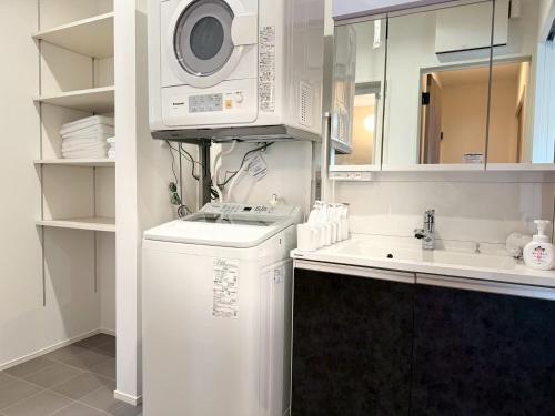 a white kitchen with a washing machine and a sink at Akikawa Koshi 12 プレミアム木造 一棟貸切ヴィラ in Yuge