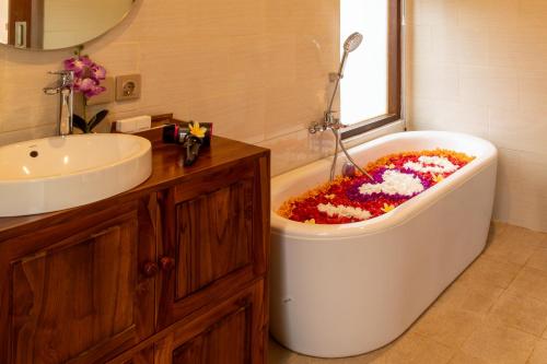 a bathroom with a bath tub filled with flowers at Umah Uwa Villa Ubud in Tegalalang