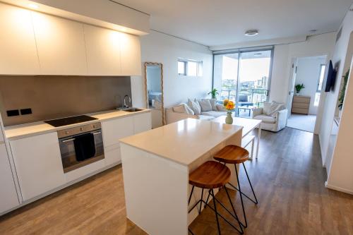 a kitchen with white cabinets and a kitchen island with stools at Modern City Pad, 1-Min to Showgrounds in Brisbane