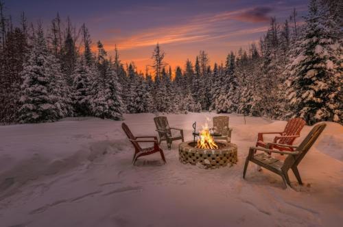 a fire pit in the snow with chairs and trees at Private Forest Spa Retreat - Modern Chalet in Chertsey