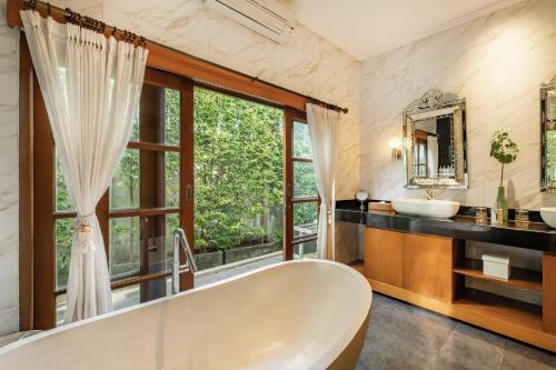 a bath tub in a bathroom with a window at Villa Balidamai in Kerobokan