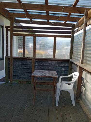 a wooden table and a white chair on a porch at Budget accommodations 2 in Papamoa