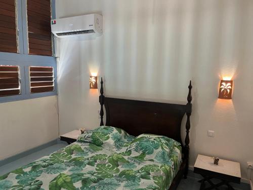 a bedroom with a bed and two tables with lights at APPARTEMENT LOTUS avec PISCINE et à 3 min de la PLAGE Pointe Marin in Sainte-Anne