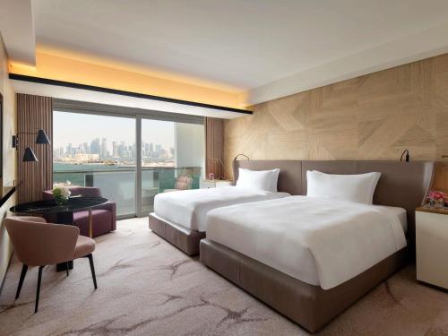 una grande camera da letto con due letti e una grande finestra di Rixos Gulf Hotel Doha a Doha