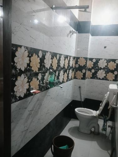 a bathroom with a toilet and flowers on the wall at Rajwaniya home in Jaipur
