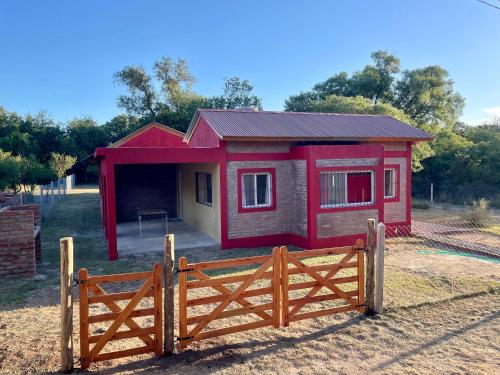a small red house with a fence in front of it at Las Mariposas in Merlo