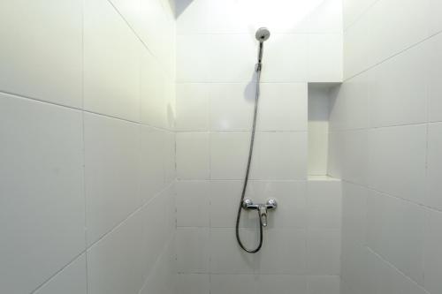 a shower with a hose in a white tiled bathroom at Ketawa Pet Friendly Hotel in Chiang Mai