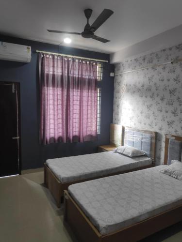 a bedroom with two beds and a ceiling fan at The Siiying in Pāsighāt