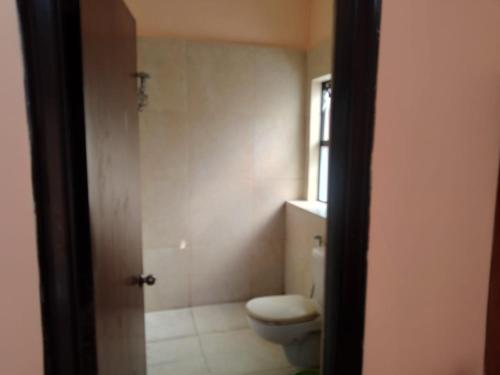 a bathroom with a toilet and a window at Surabhi Gardenia 28B-C in Raichak
