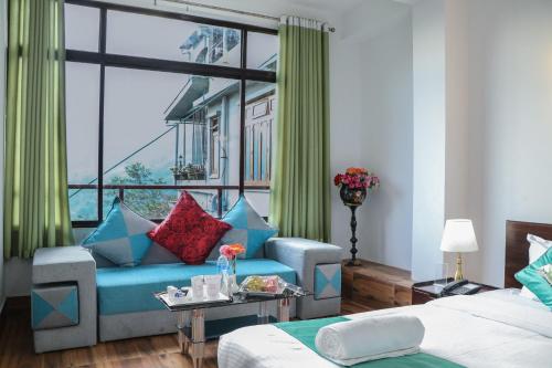 a living room with a blue couch and a window at HOTEL GREENERY VIEW in Gangtok