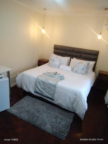 a bedroom with a large bed with white sheets and pillows at Nkosazana Guest House in Durban