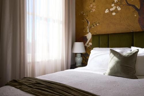 a bedroom with a white bed with a window and a lamp at The Royal Queenscliff in Queenscliff