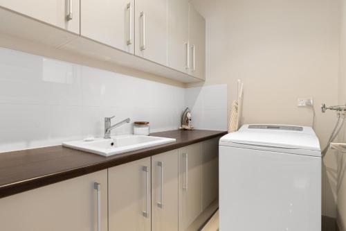 a white kitchen with a sink and a dishwasher at Walk to the Mandurah Foreshore & Marina in Mandurah