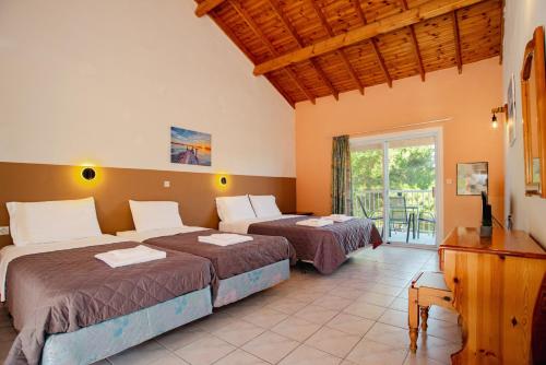 a bedroom with two beds and a balcony at Gardenos Hotel in Vitalades