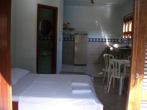 a bedroom with a bed and a kitchen with a table at Pousada Farol da Barra in Florianópolis